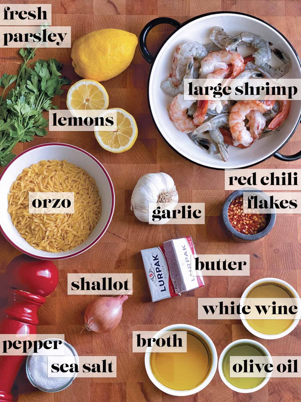 Ingredients on a butcher block for lemon garlic shrimp orzo.