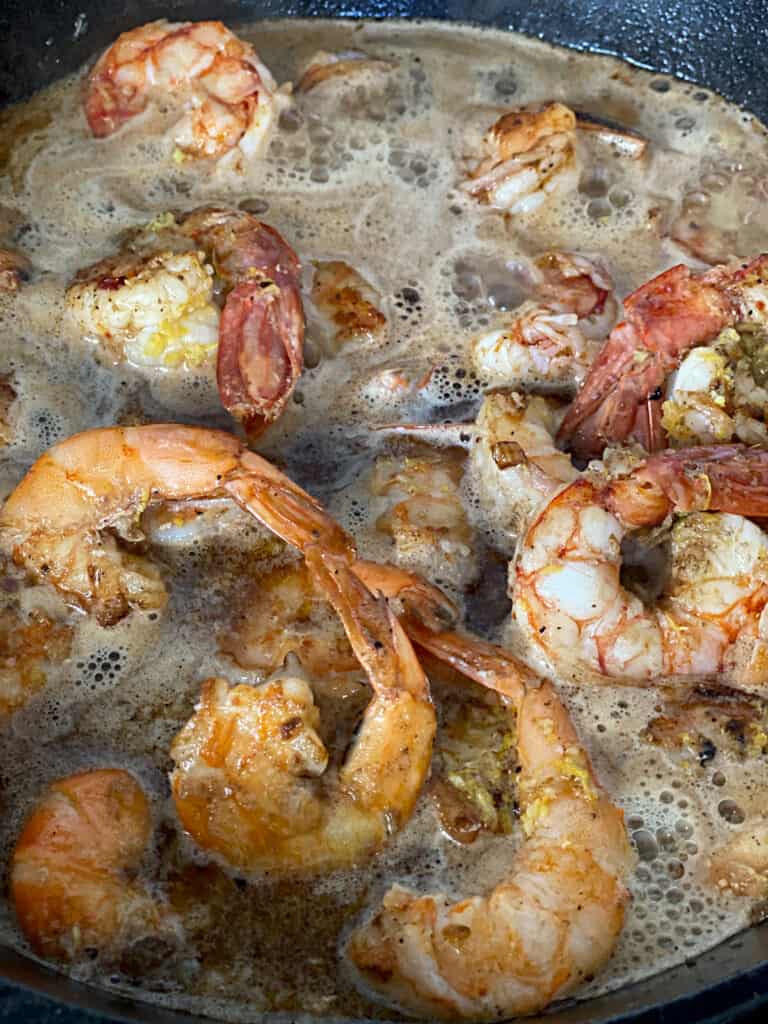 Shrimp in a skillet simmering in sauce.