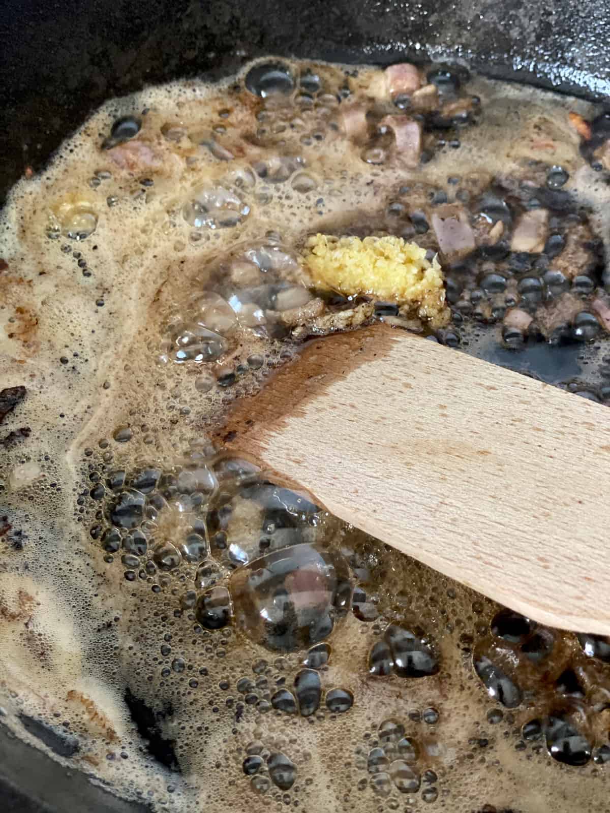 Browned butter in a skillet, garlic and a wooden spoon.