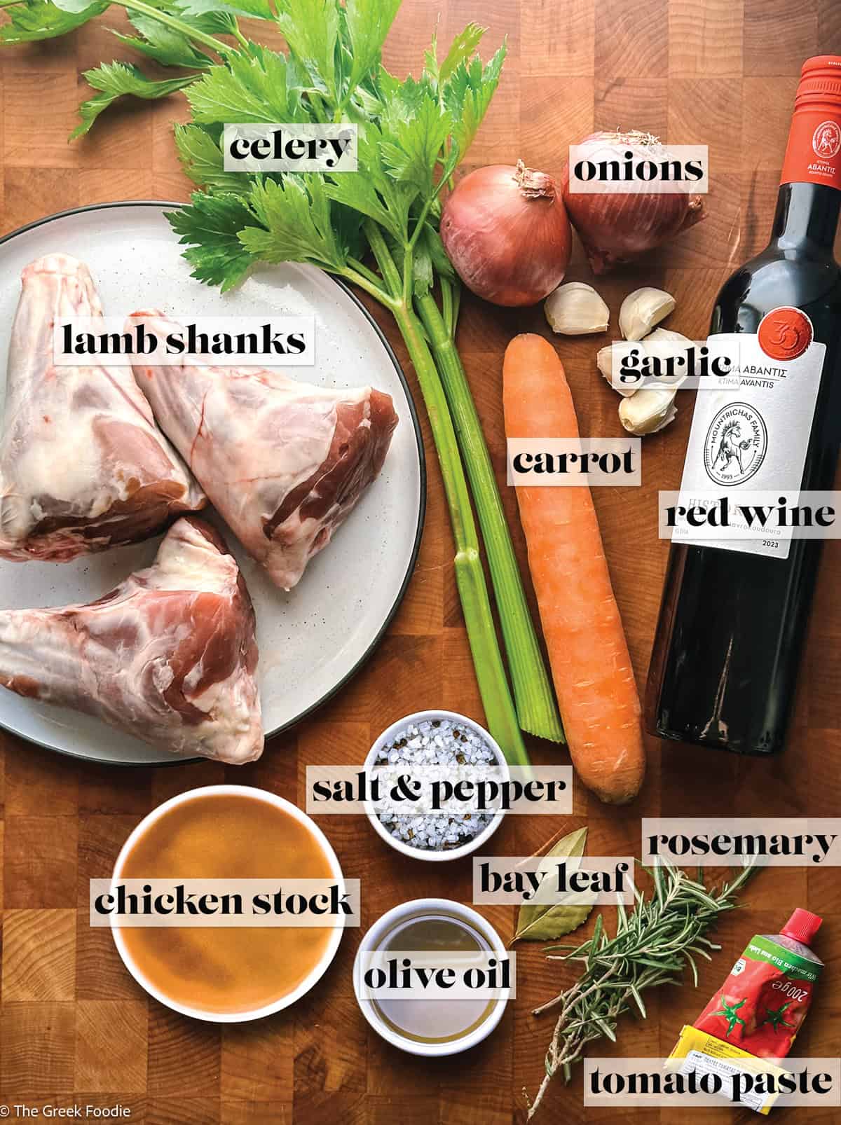 Lamb shanks, celery, carrot, onions, wine, garlic, broth, olive oil, sea salt, pepper and tomato paste on a wooden surface