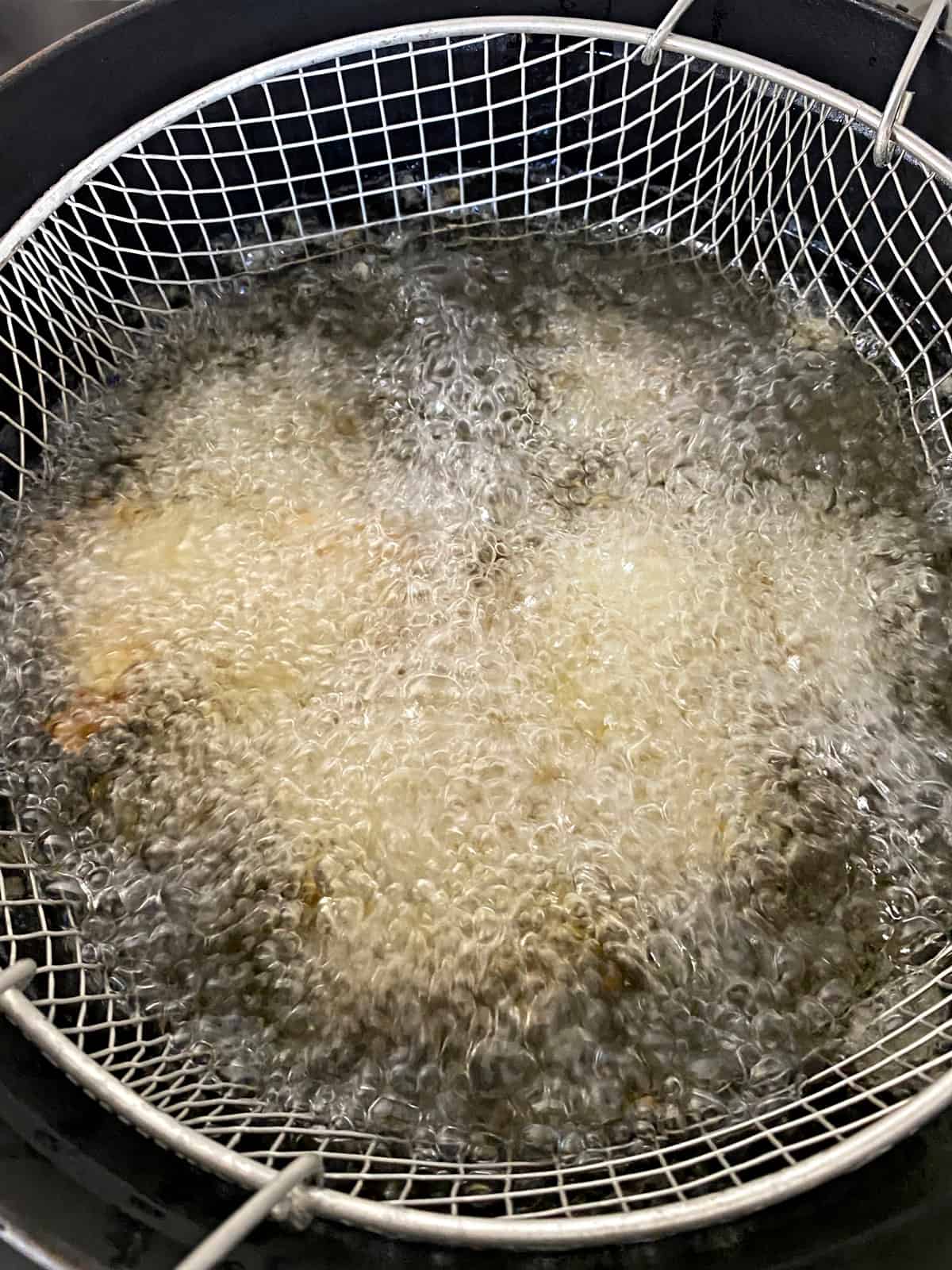 A frying wire basket in hot oil.