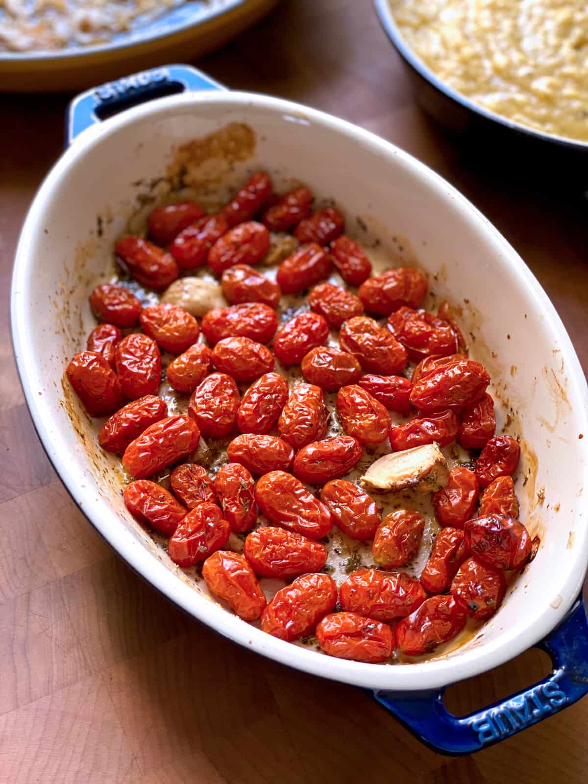 Roasted tomatoes in an oval pan with garlic and seasonings.