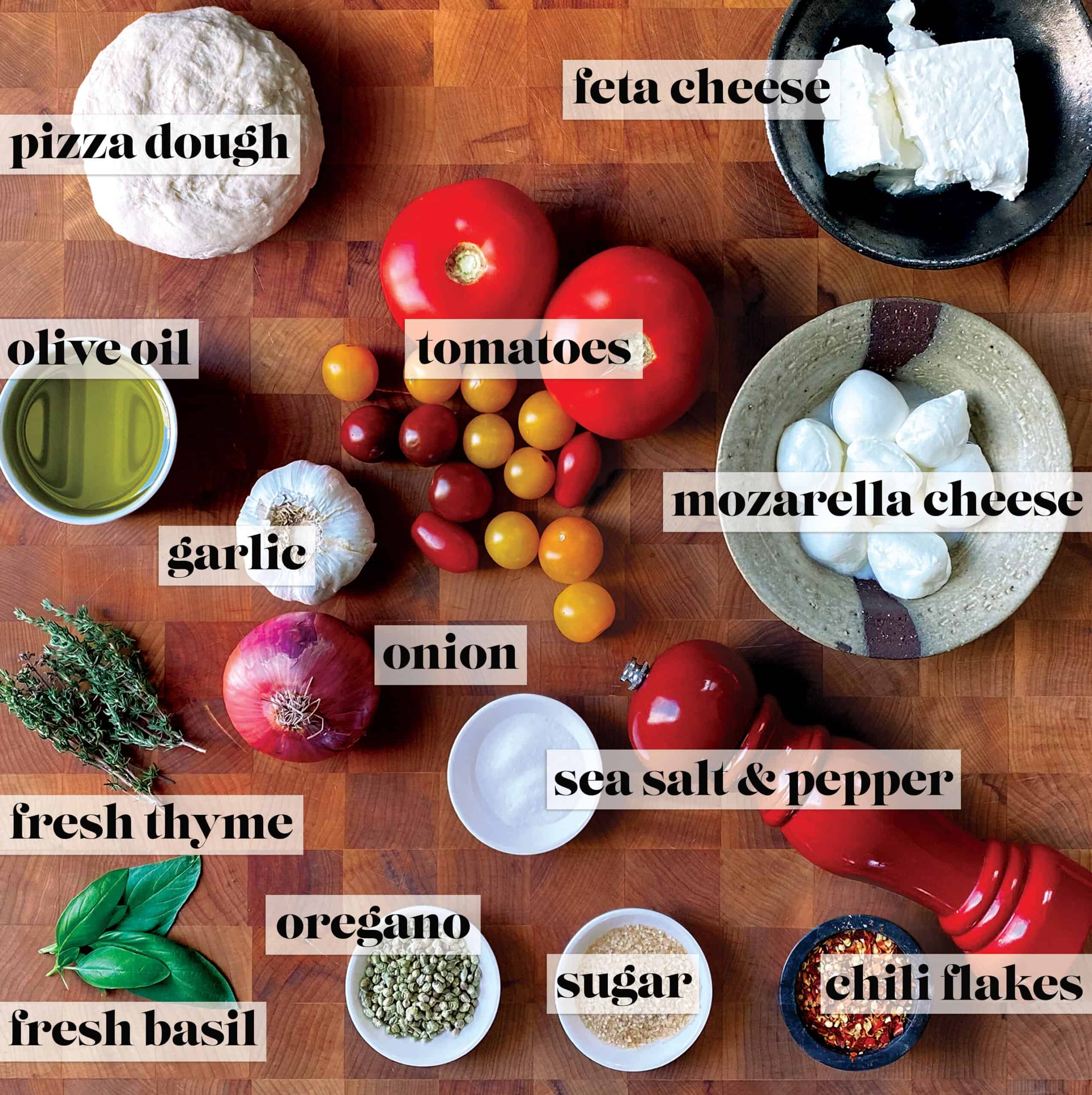 Ingredients for pizza with feta and tomatoes on a wooden board.