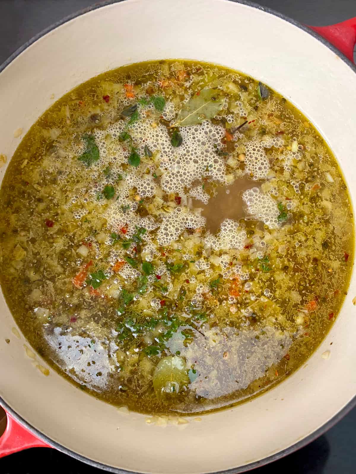 Lentils, vegetables and broth in a stockpot.