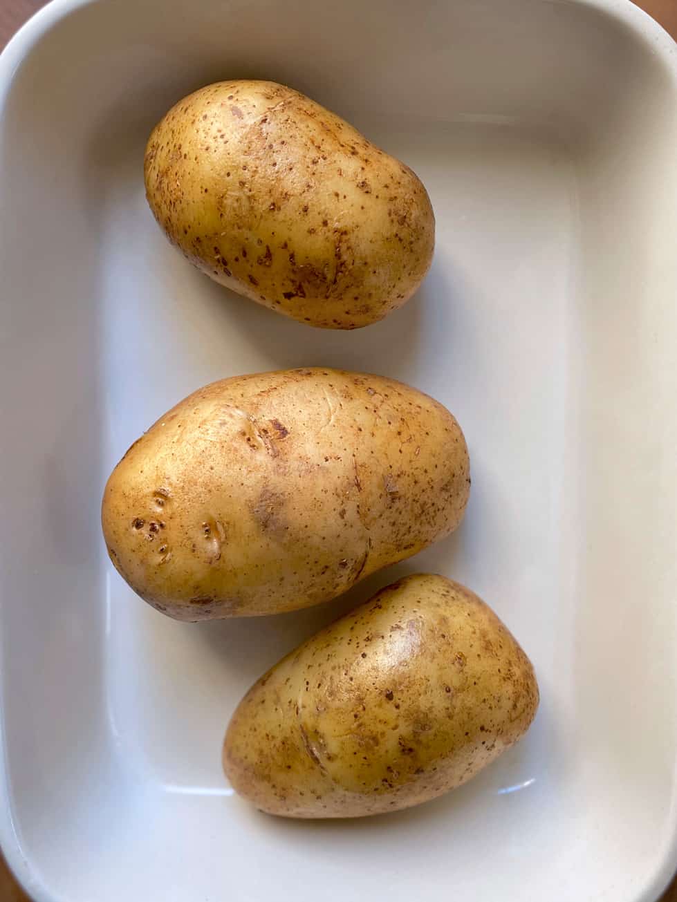Three potatoes in a baking pan.