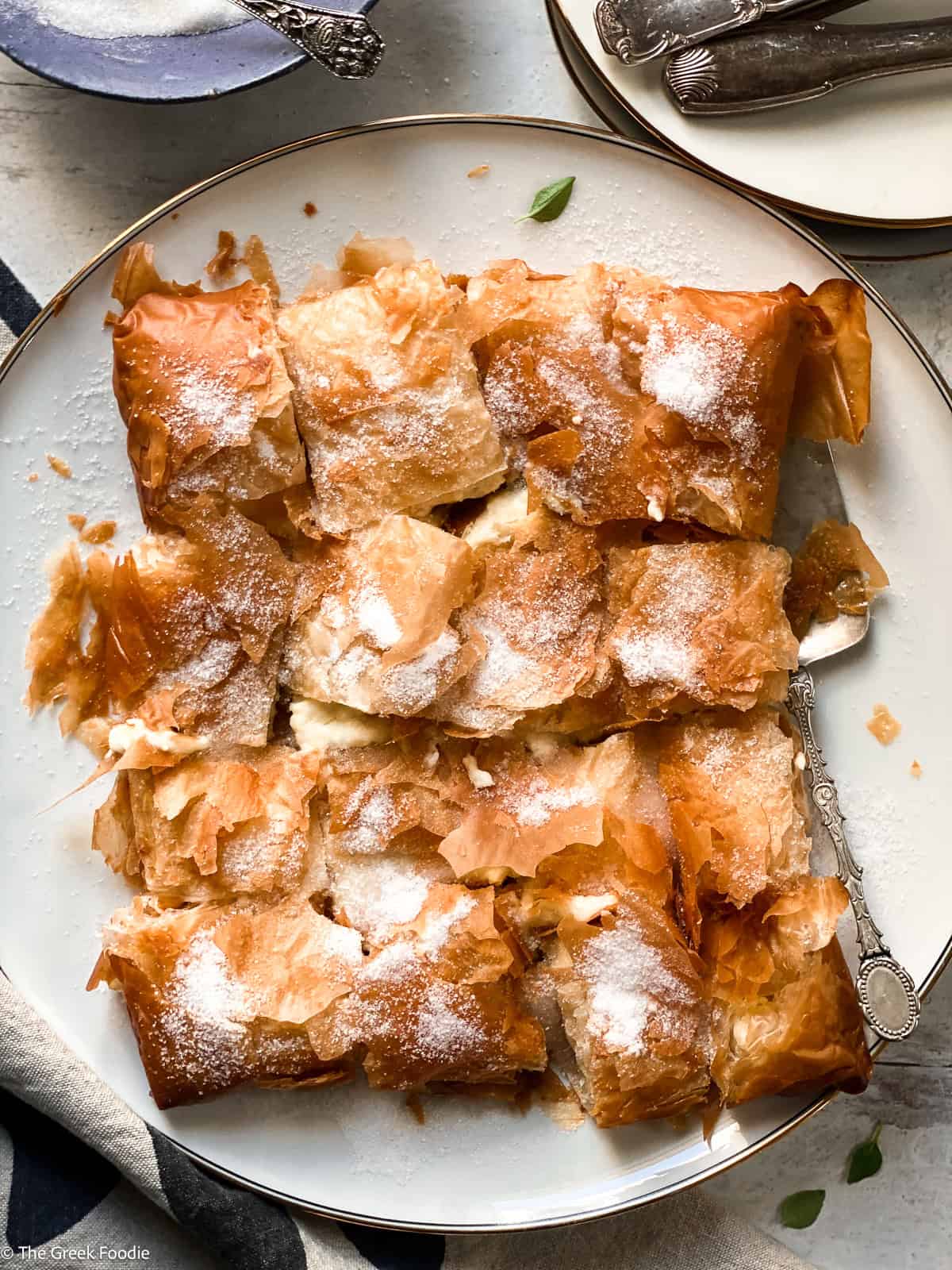 Bougatsa Chaniotiki – Cretan cheese phyllo pastry cut into pieces on a white plate