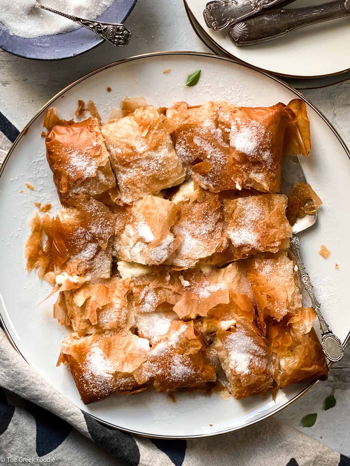 Bougatsa Chaniotiki – Cretan cheese phyllo pastry cut into pieces on a white plate