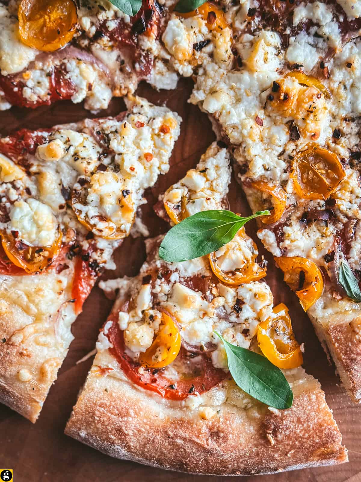 Close-up of feta pizza showing golden, creamy baked feta over melted mozzarella and tomatoes