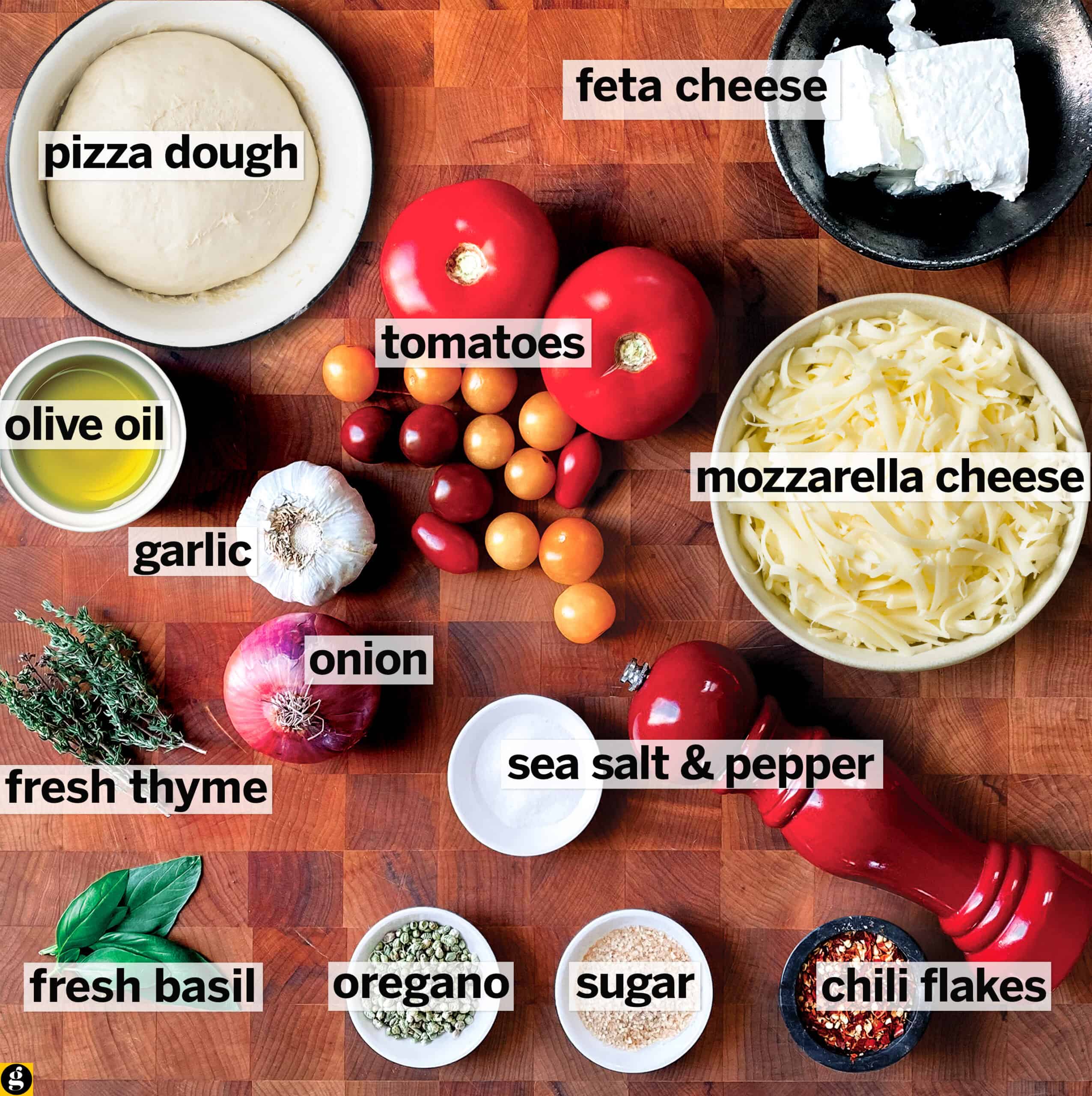 Ingredients for pizza with feta and tomatoes on a wooden board.
