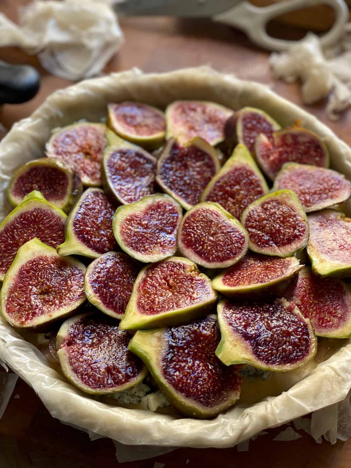 A tart pan layered with phyllo sheets filled with sliced figs.