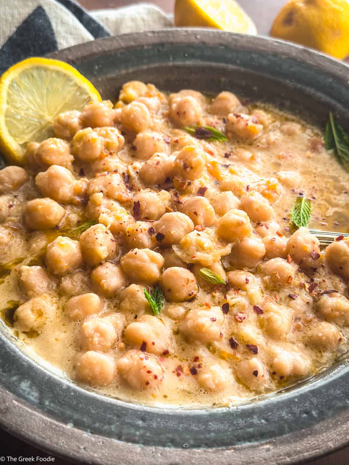 A bowl with chickpea soup, and a lemon slice.