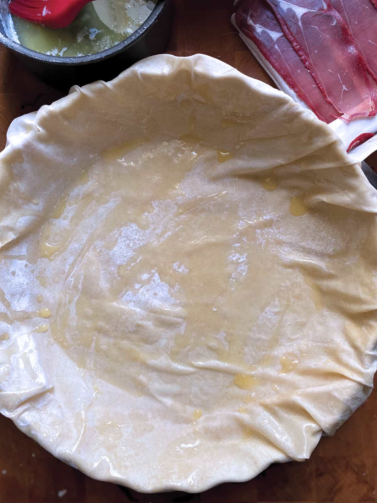 Phyllo sheets laid down on a round baking pan.