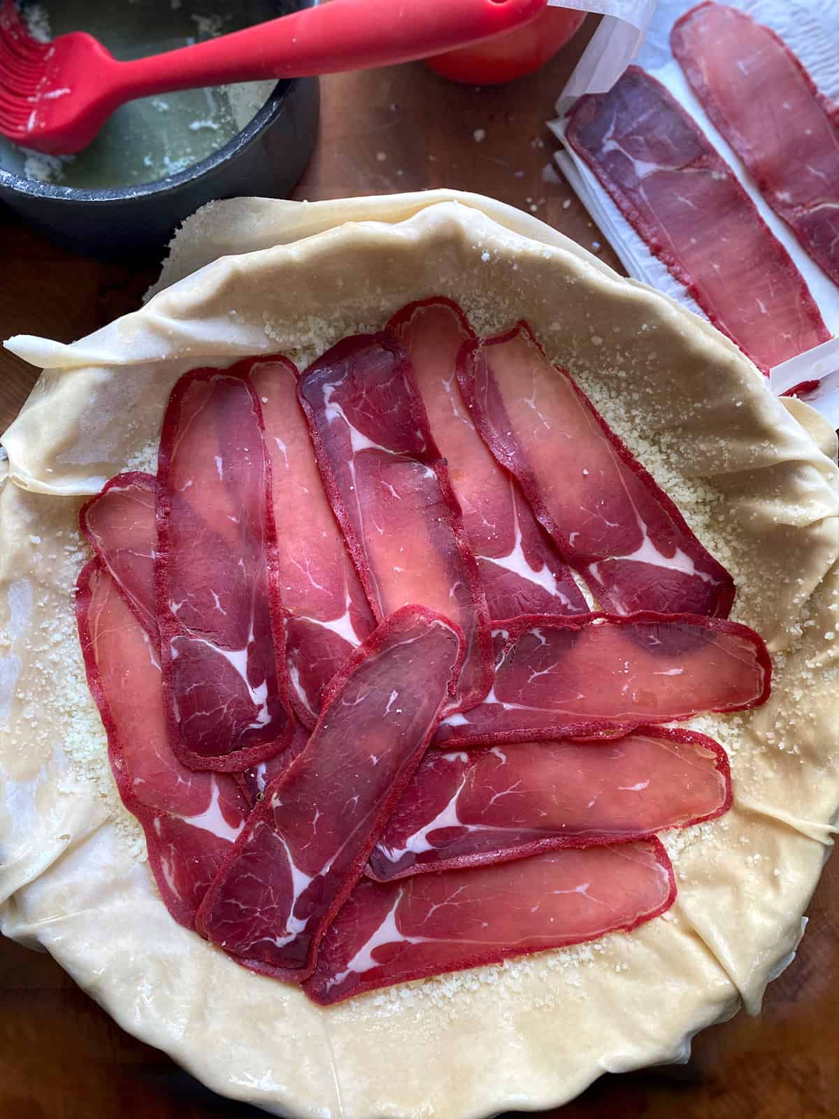 Pastourma slices and phyllo sheets in a  baking pan.