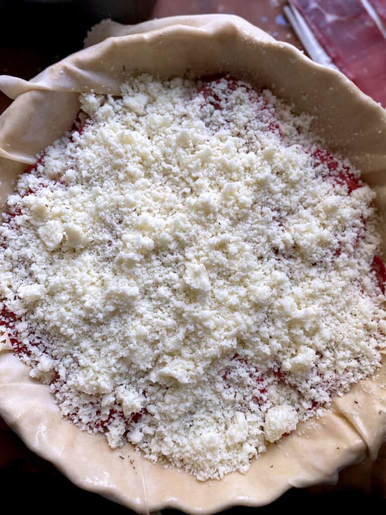 Grated cheese and phyllo sheets in a round baking pan.