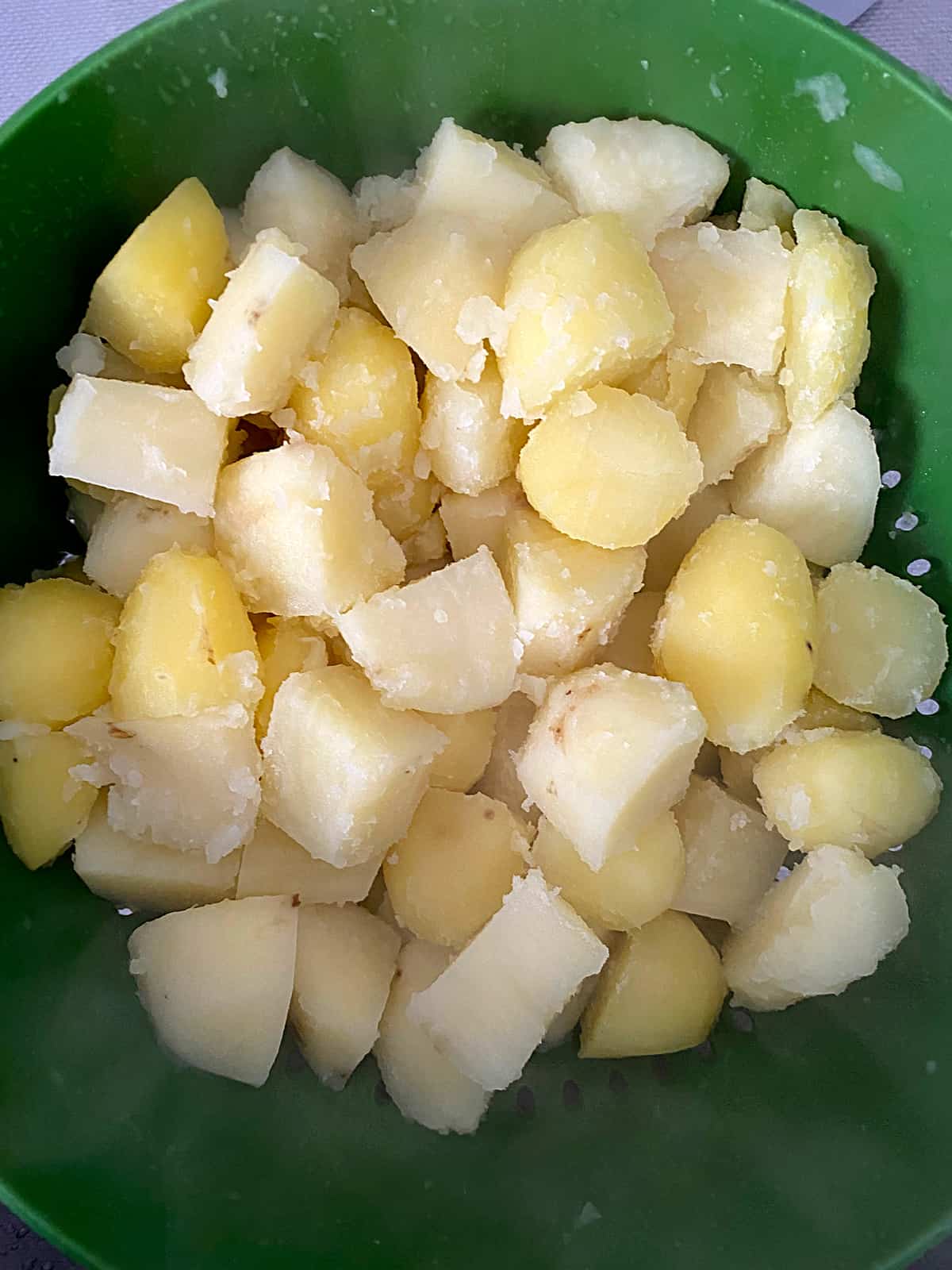 Boiled potatoes with fluffed up edges in a colander.