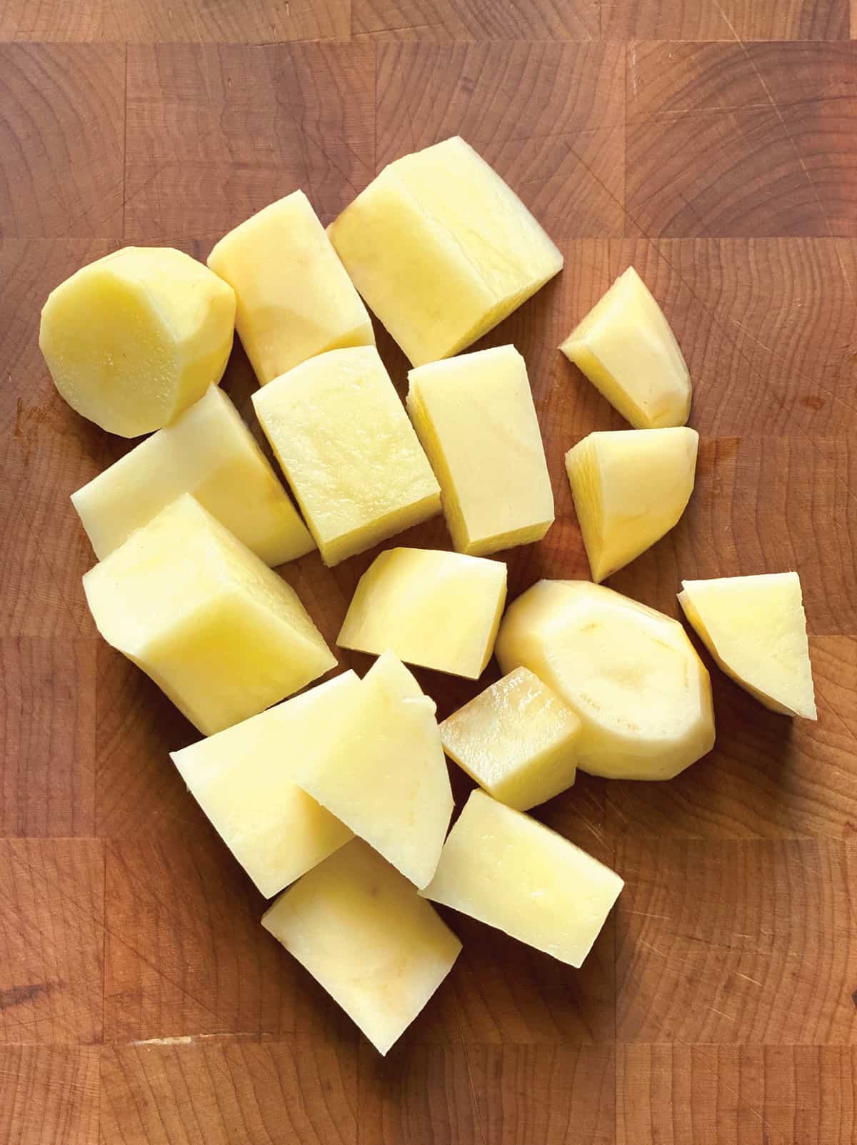 Small potato pieces on a butcher block.
