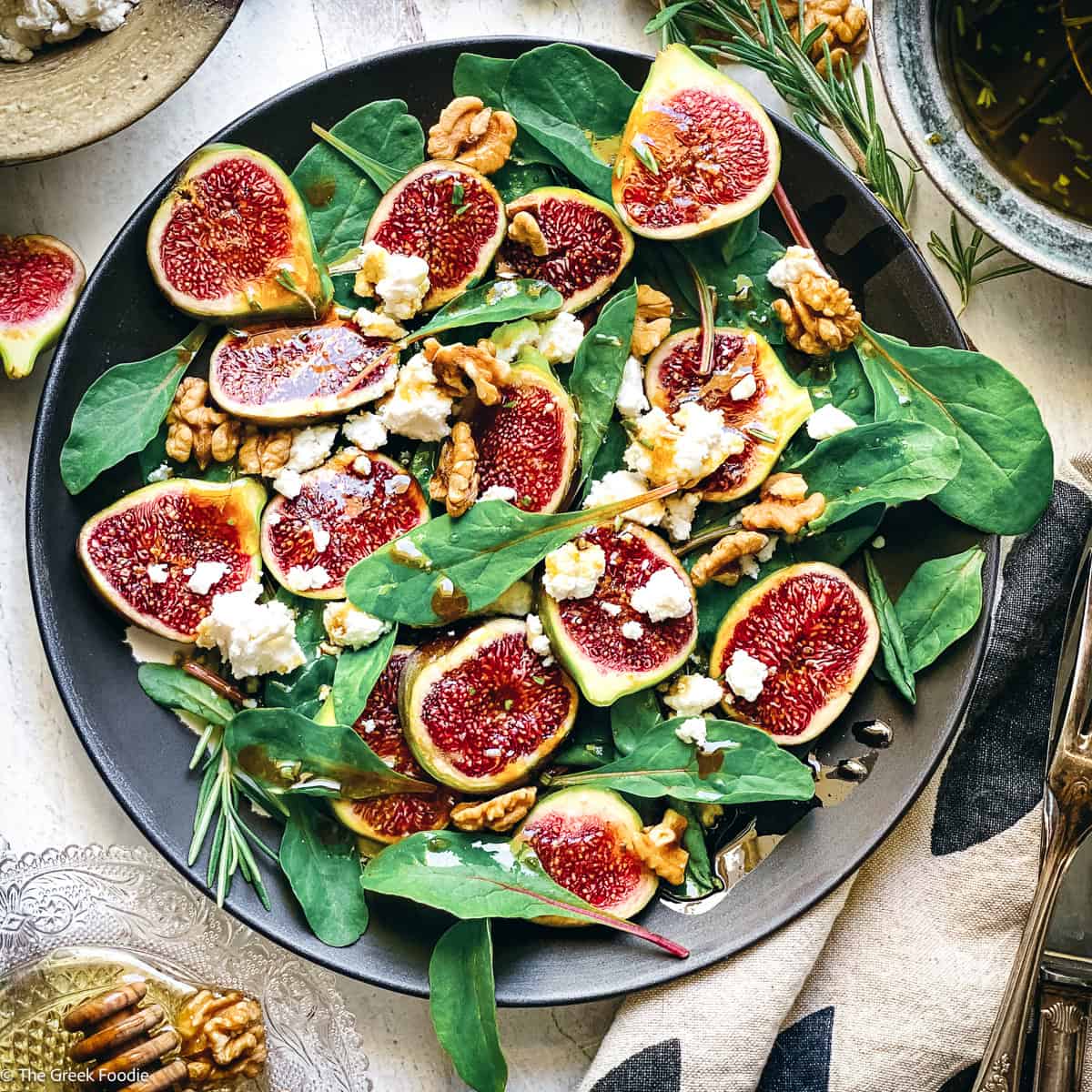 Close overhead shot of fig salad, showing the cut faces of the figs, walnut halves and crumbled white cheese.
