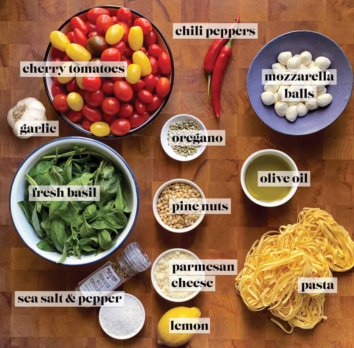 All the ingredients for making a cherry tomato pasta sauce on a butcher block.