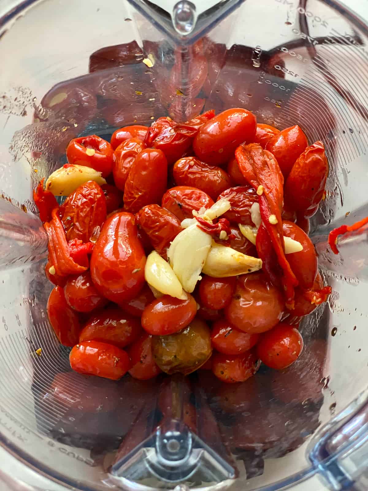 Roasted cherry tomatoes, garlic and chili peppers inside a blender.