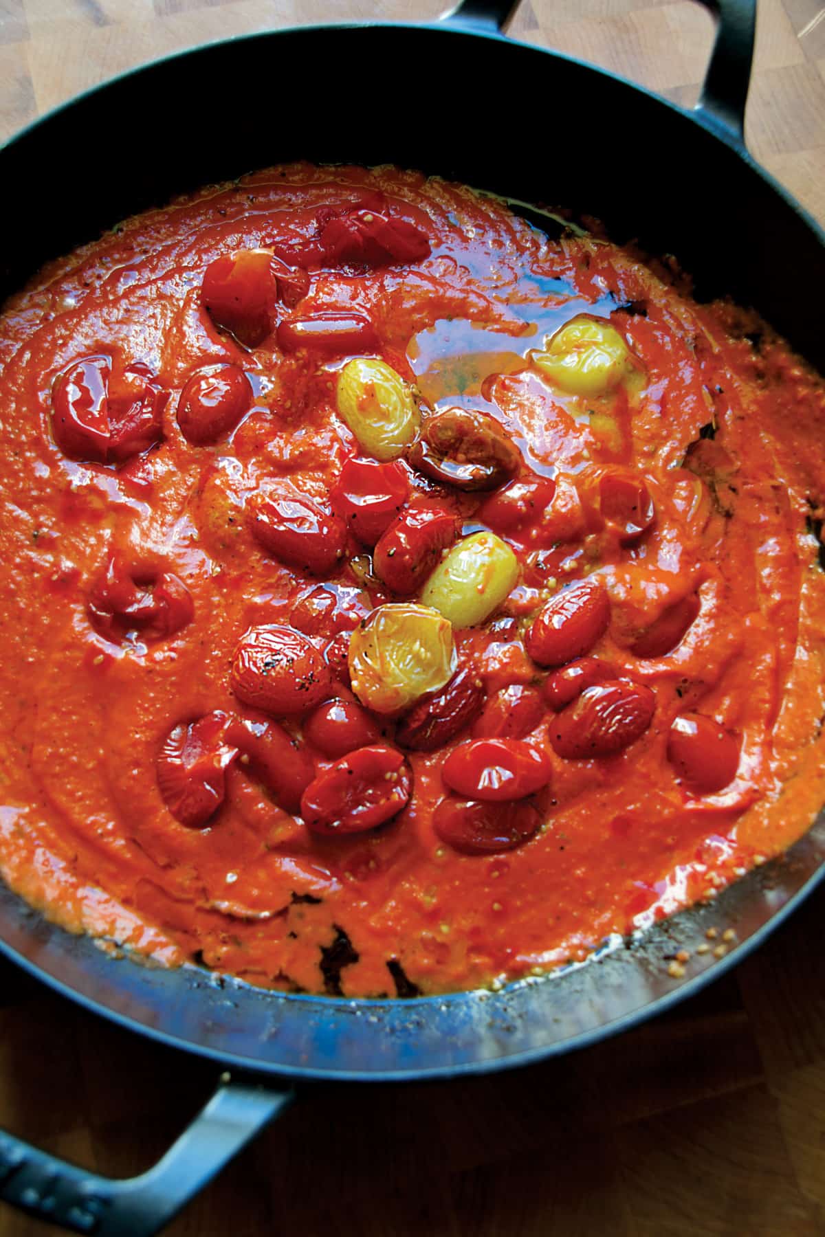 Creamy tomato sauce mixed with roasted cherry tomatoes in a cast iron pan.