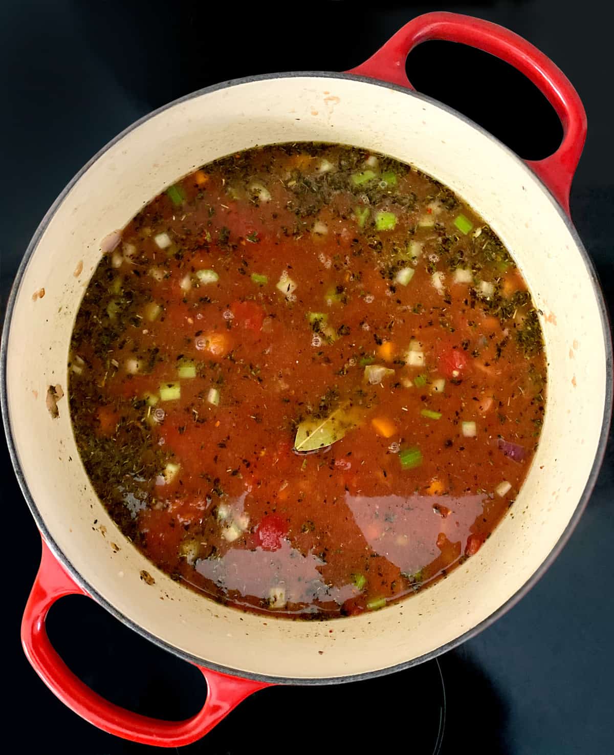 Cut up sausage and vegetables in a tomato broth in a stockpot.