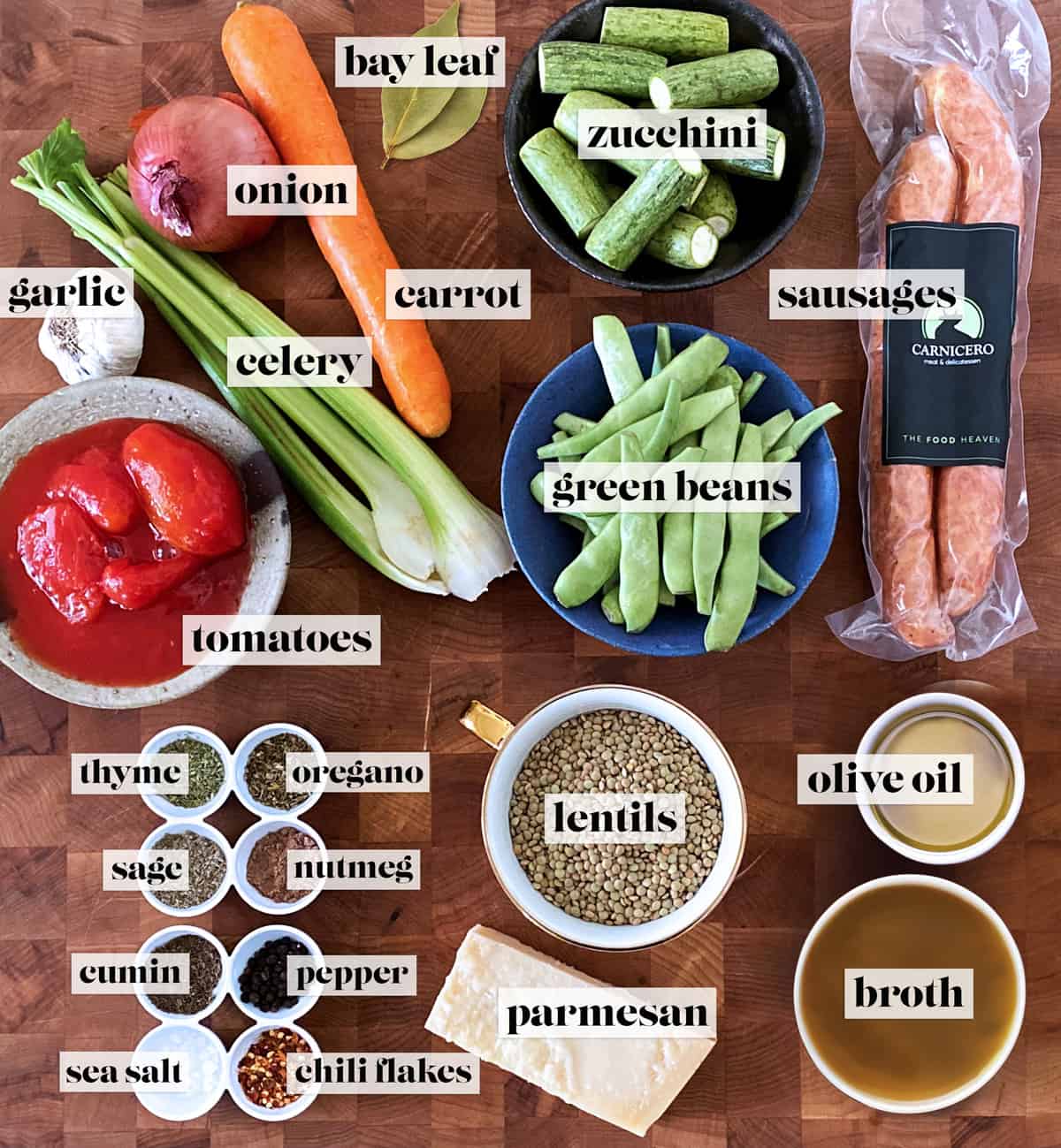 All the ingredients for making sausage lentil soup on a butcher block.