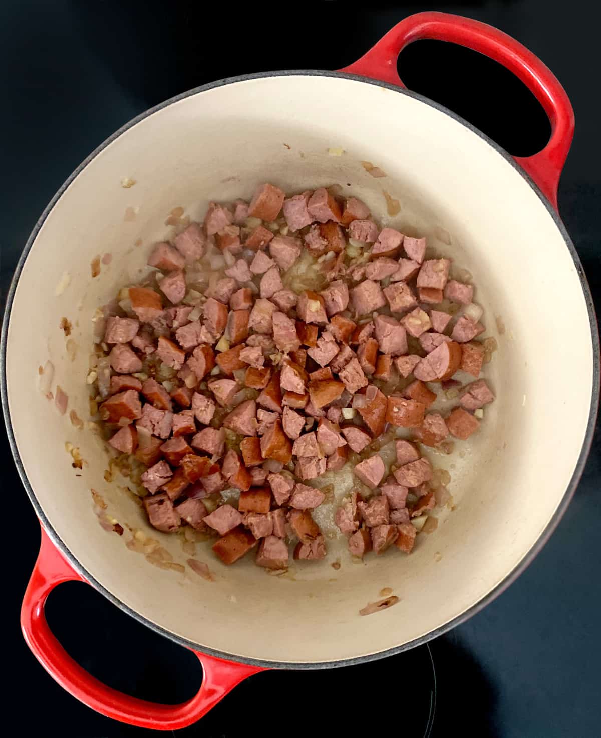 Cut up sausage and diced onion with olive oil in a stockpot.