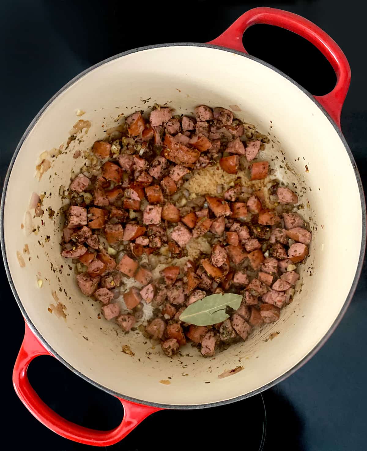 Cut up sausage, diced onion and seasonings with olive oil in a stockpot.