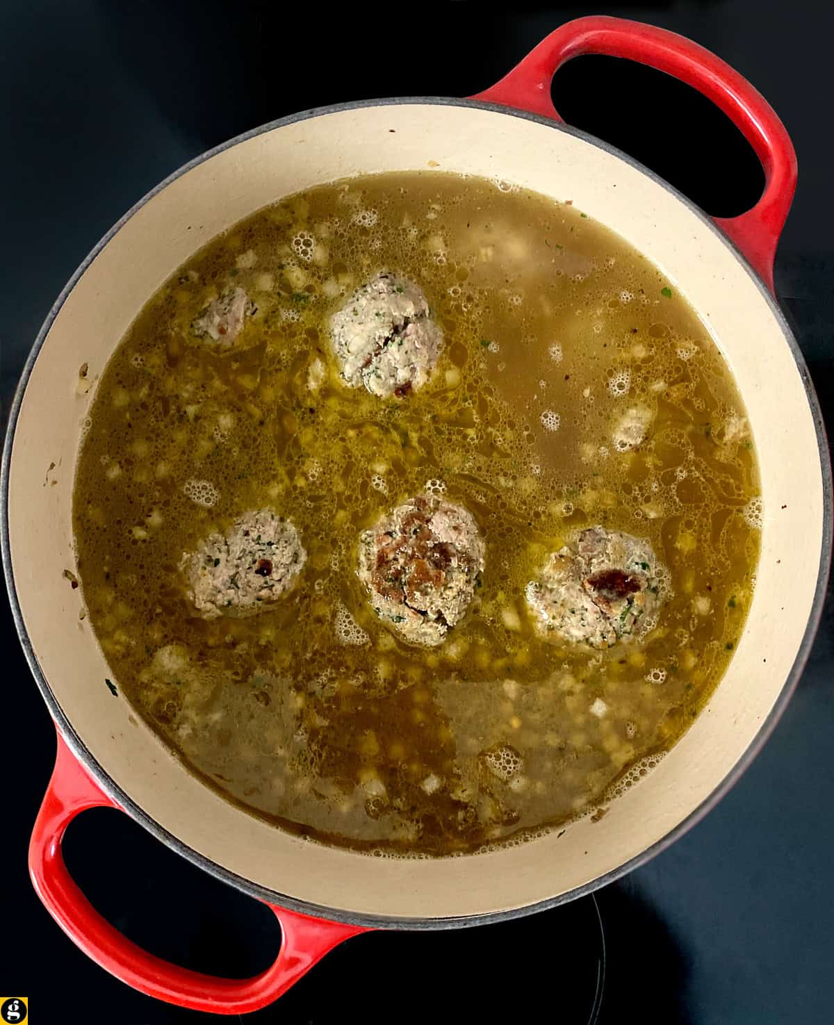 Browned meatballs returned to the Dutch oven with chicken broth.