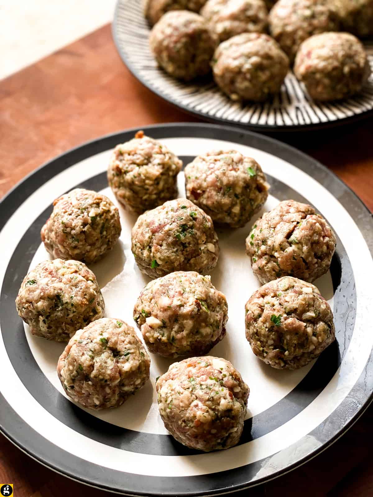 Shaped raw meatballs on plates, ready for browning.
