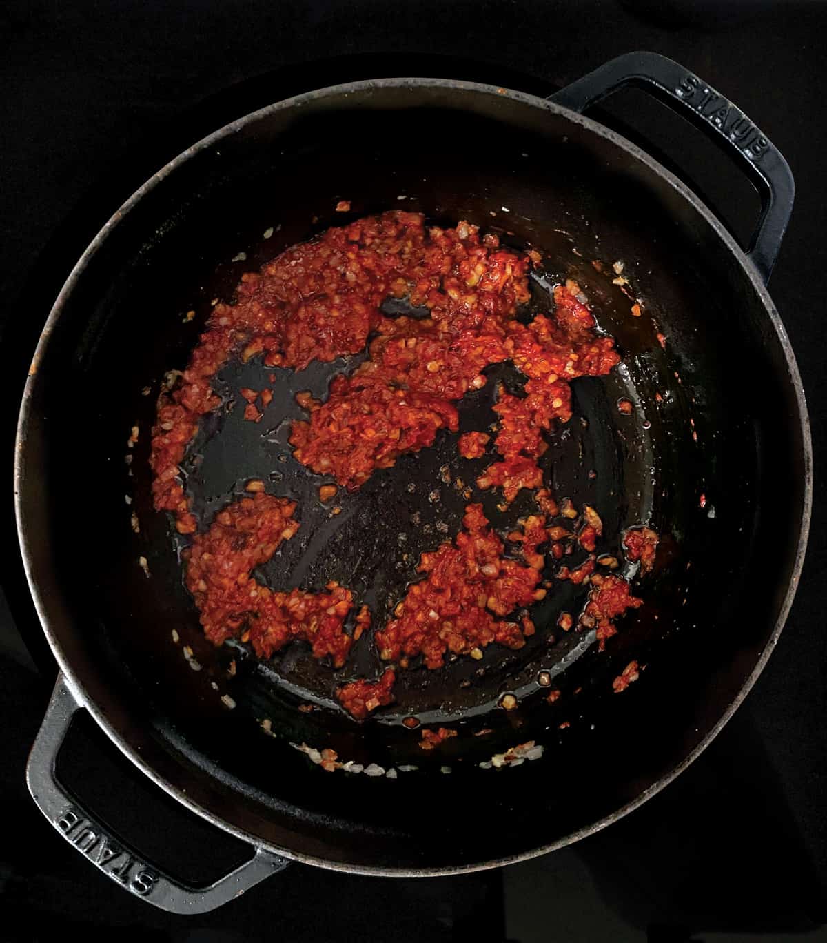 Diced onion with tomato paste and seasonings in a stockpot.

