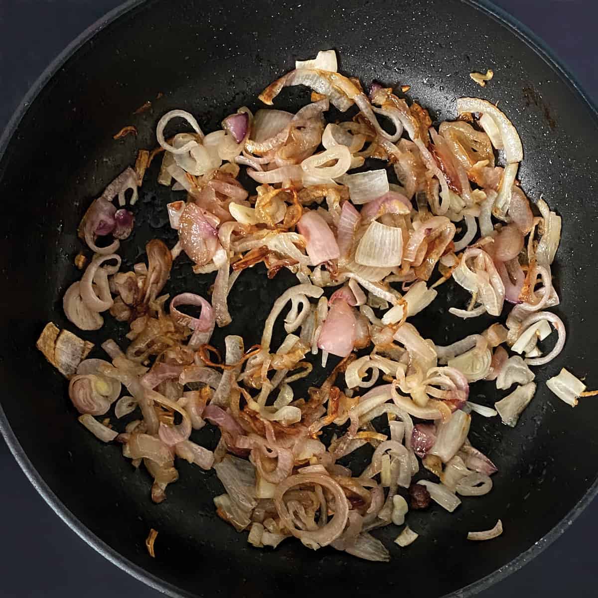 Sliced shallots and onions in a frying pan.