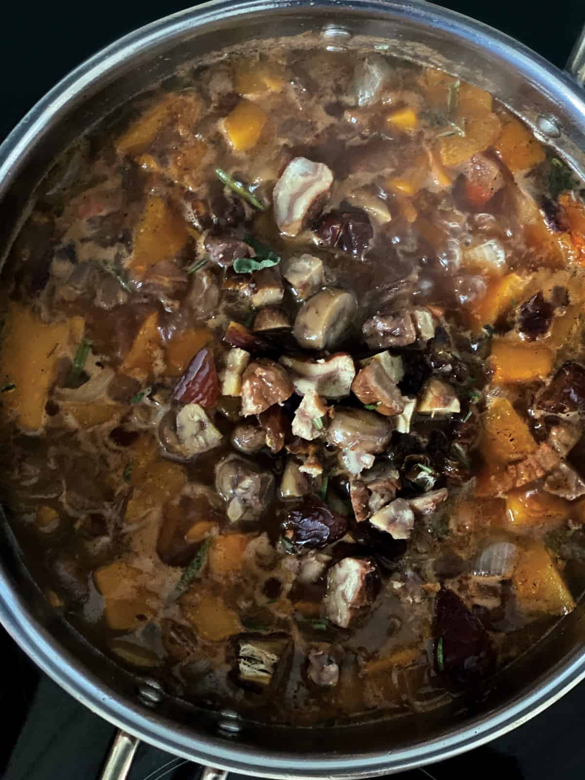Pumpkin stew with chopped chestnuts and dates on top in a deep sauce pan.