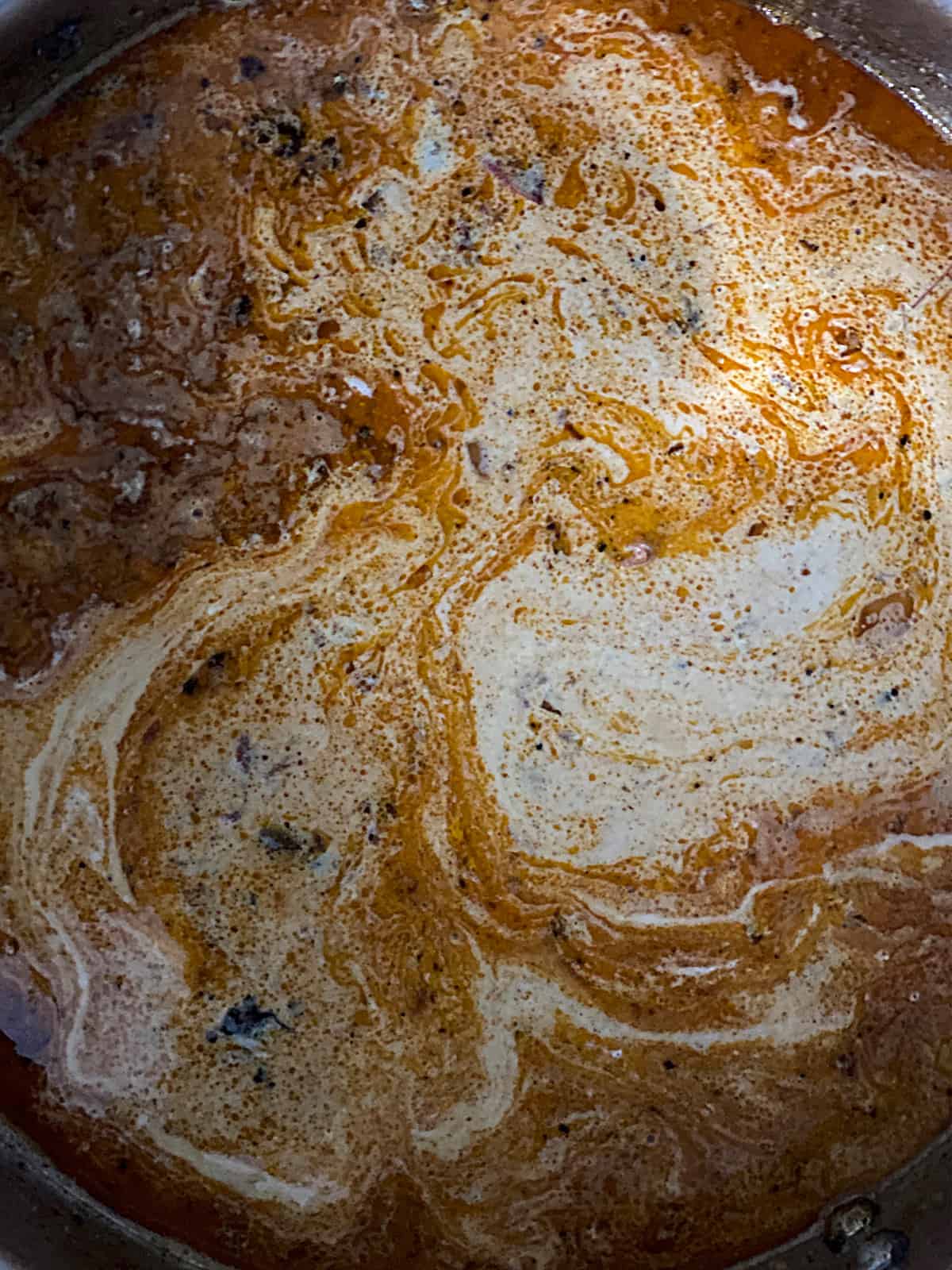 Broth and cream cooking in a saucepan.