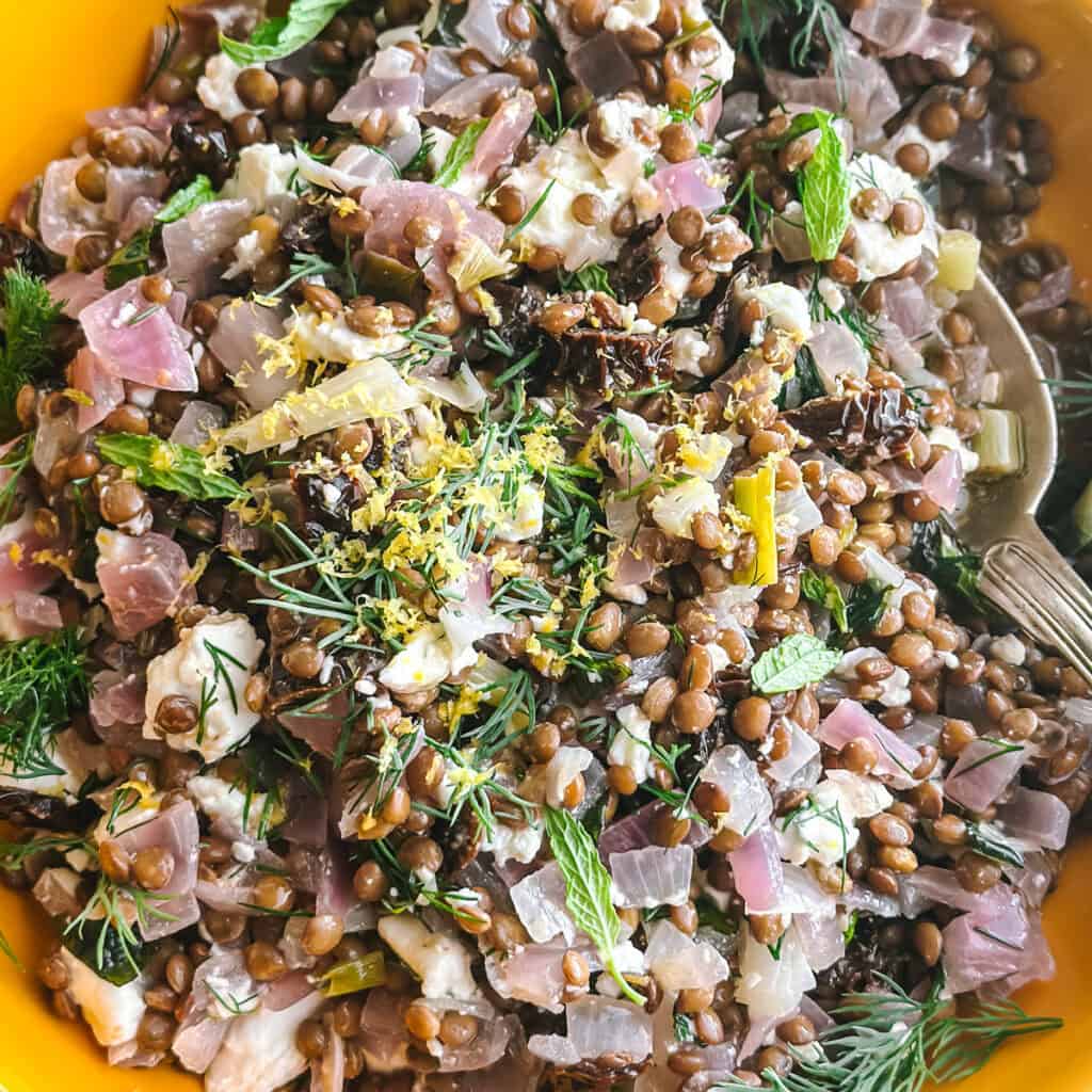 Greek lentil salad with sun-dried tomatoes, crumbled feta and fresh herbs in a bowl