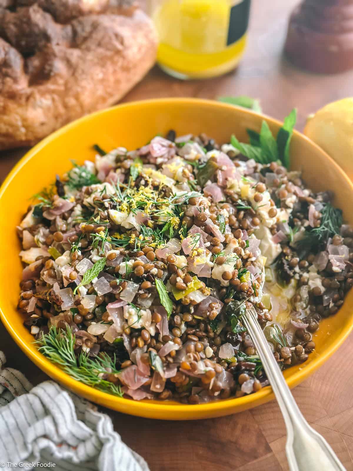 Lentil salad with feta and sun-dried tomatoes served with bread and lemon