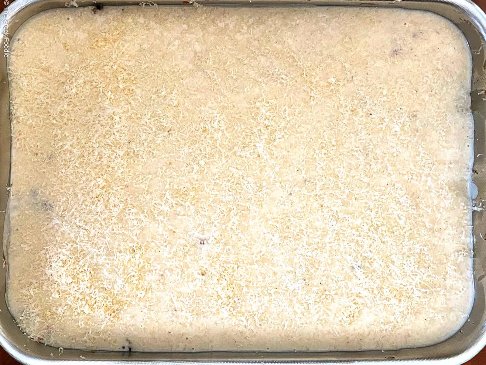 An assembled Greek moussaka with a layer of béchamel ready for the oven
