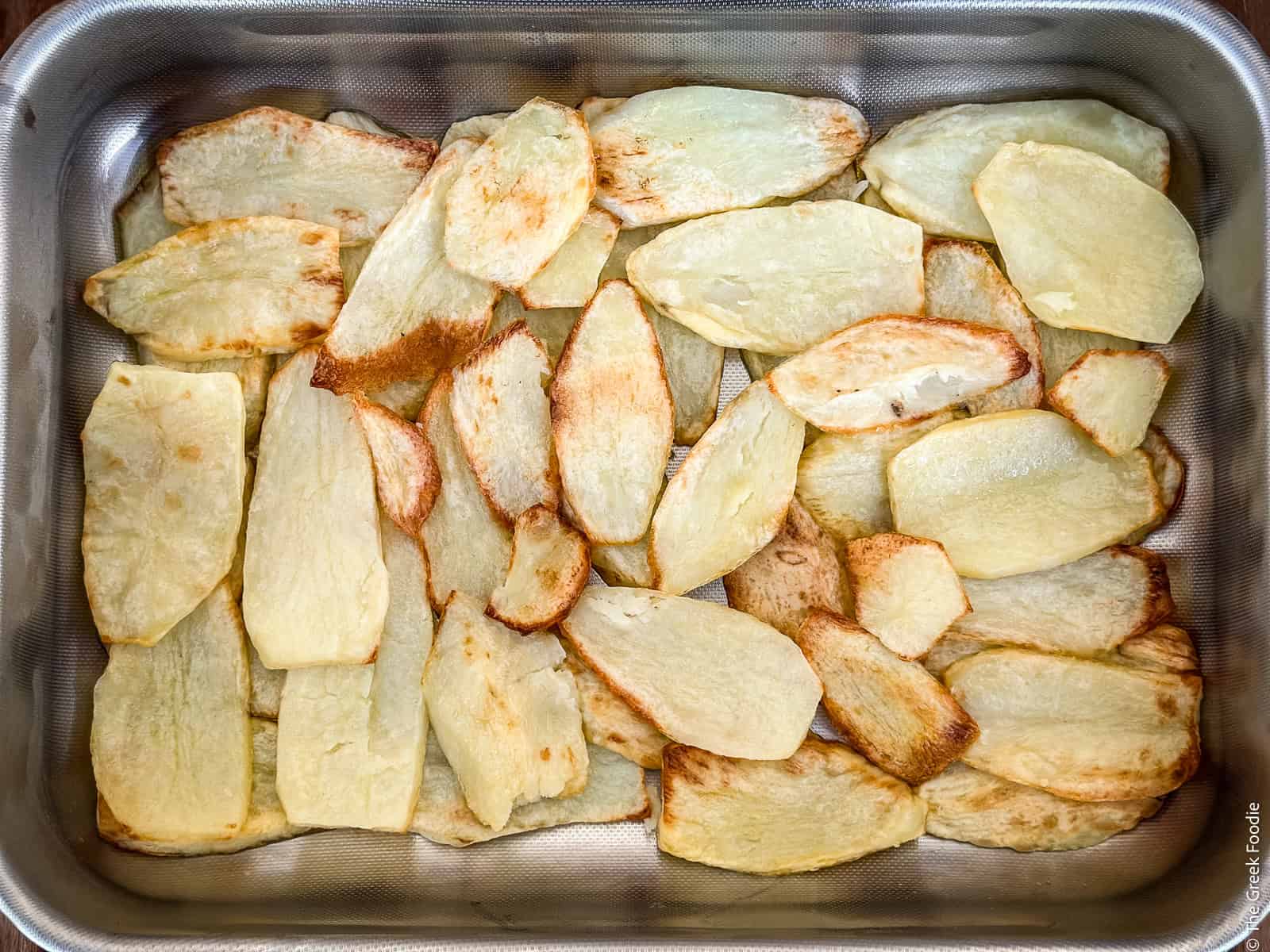 A layer of potatoes in a baking pan for Greek moussaka