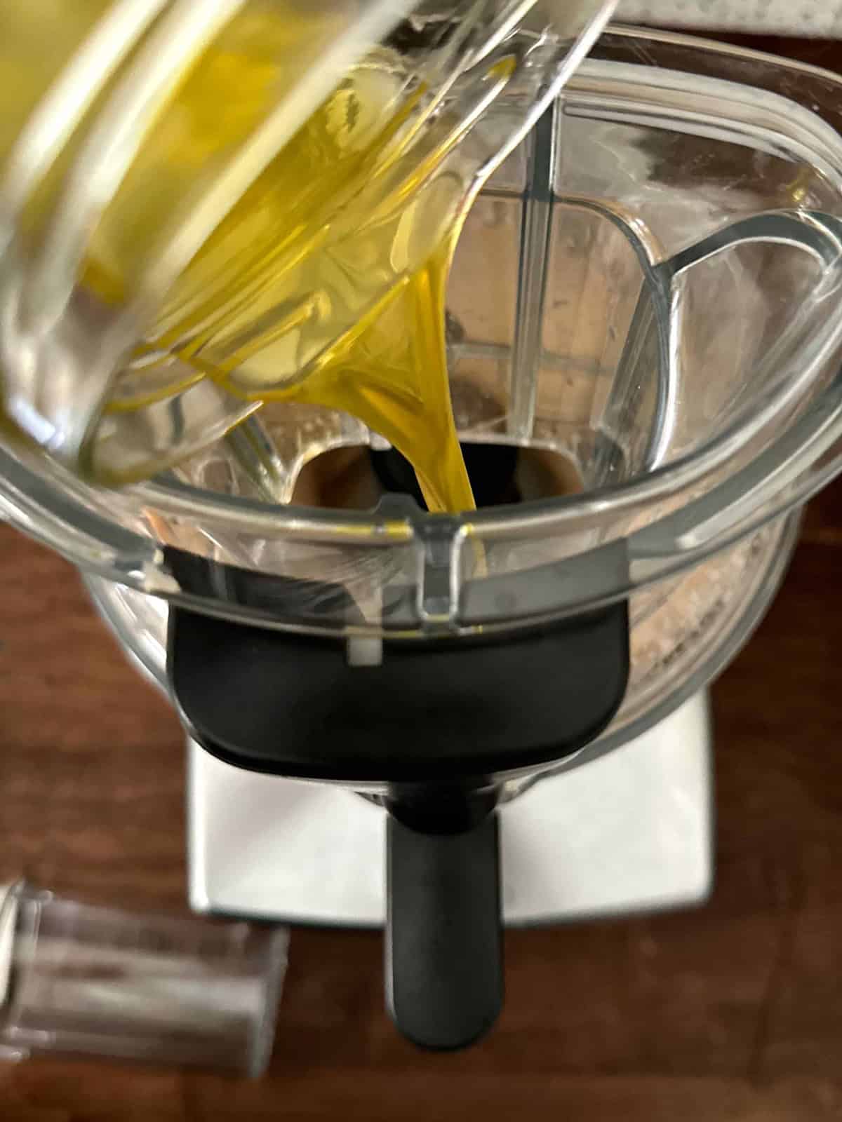 Slowly pouring olive oil into food processor while making taramosalata