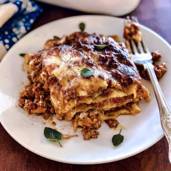 A piece of eggplant lasagna on a plate with a fork.