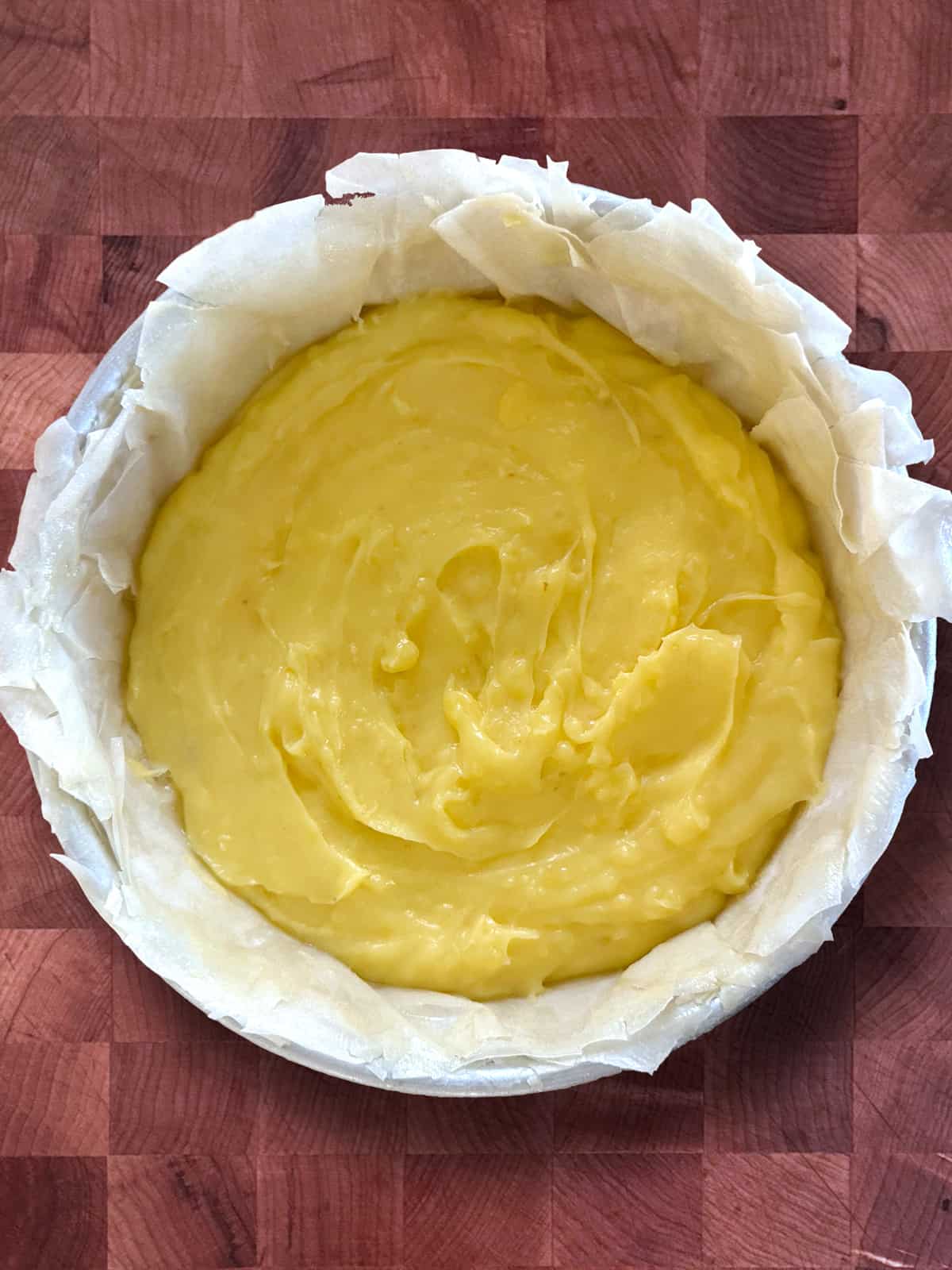A round aluminum pan lined with buttered phyllo sheets and custard.
