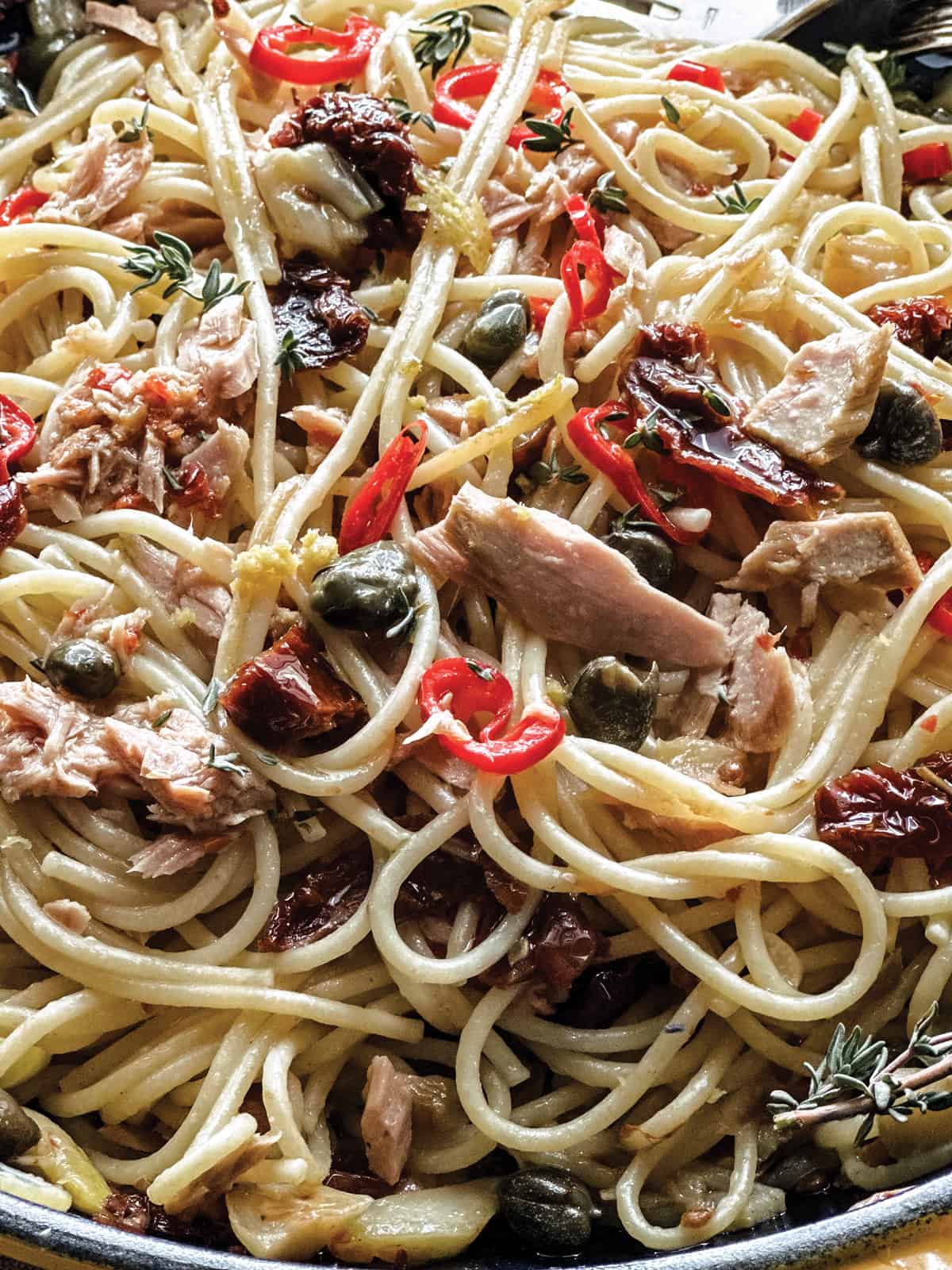  Spaghetti with capers, sun-dried tomatoes and garlic in a skillet.