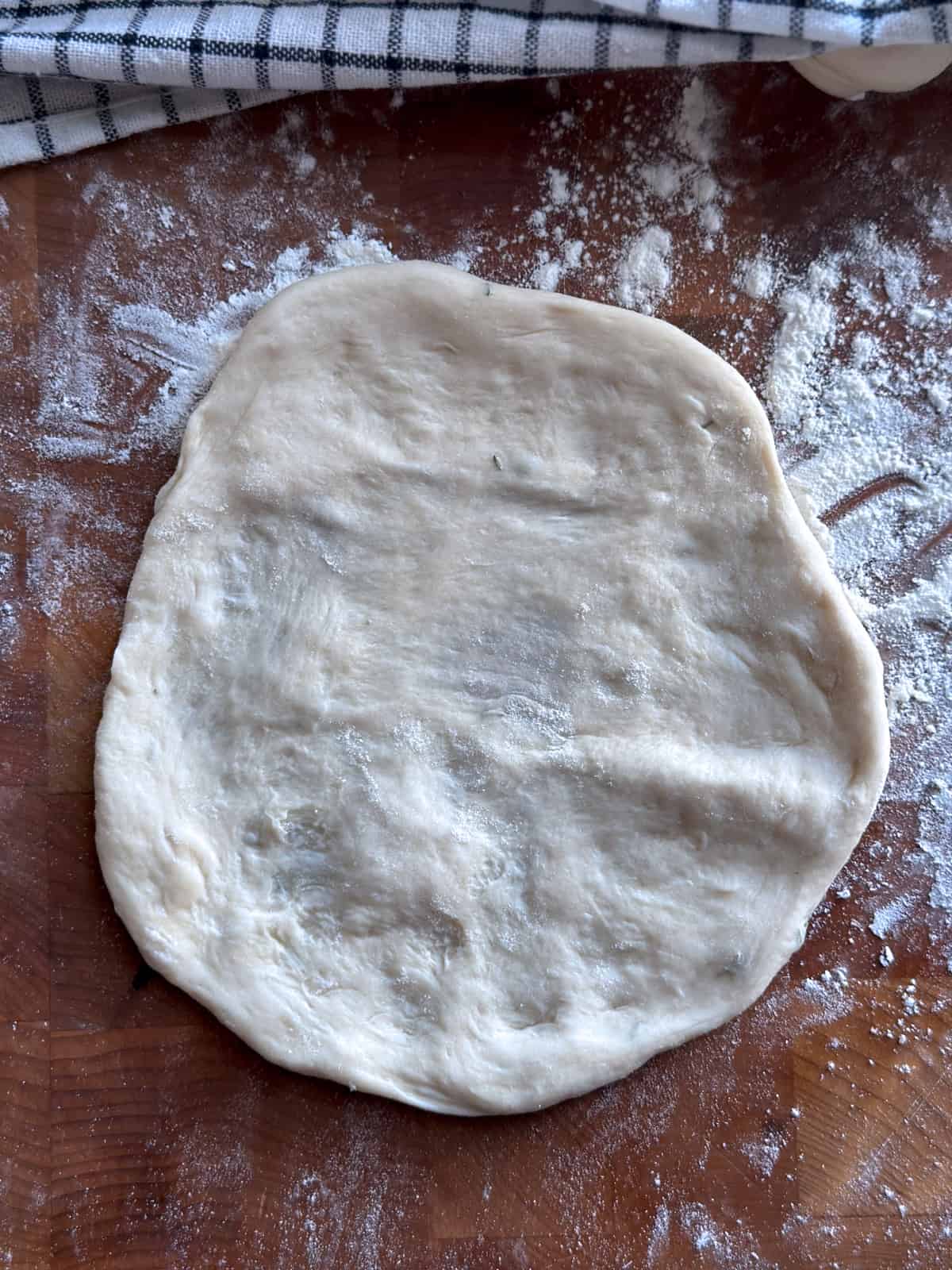 A stretched pita on a floured surface.