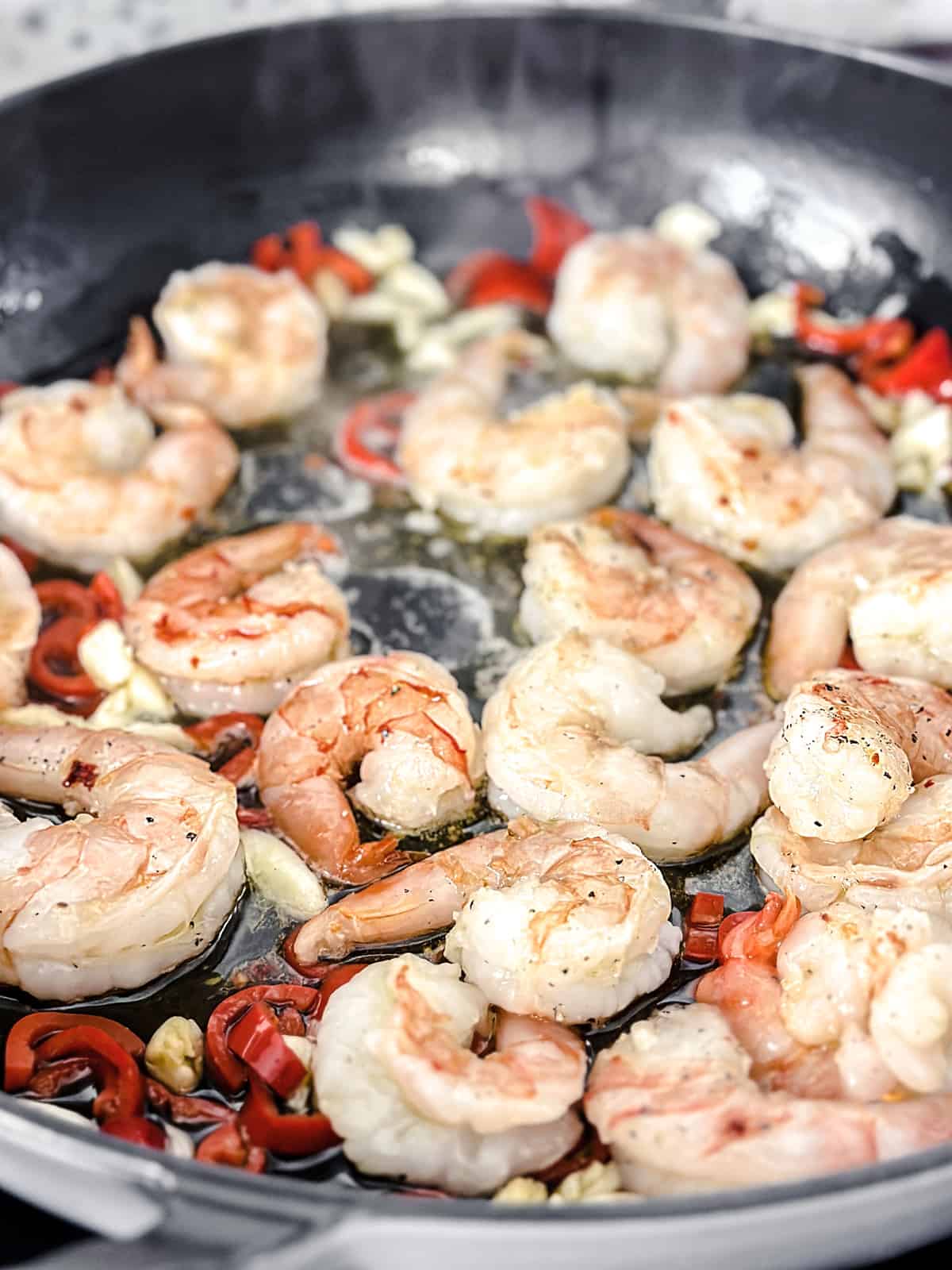 Shrimp, chopped garlic and chili peppers in olive oil in a large deep sauté pan.