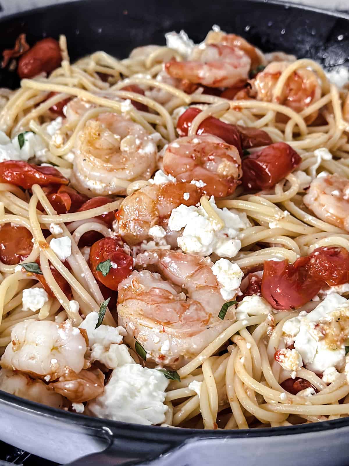 Cherry tomatoes, shrimp, and spaghetti  and chili peppers in olive oil in a large deep sauté pan.