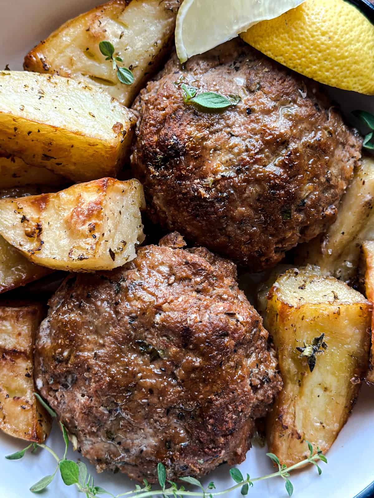 A plate with two biftekia, greek burgers and roasted potatoes.