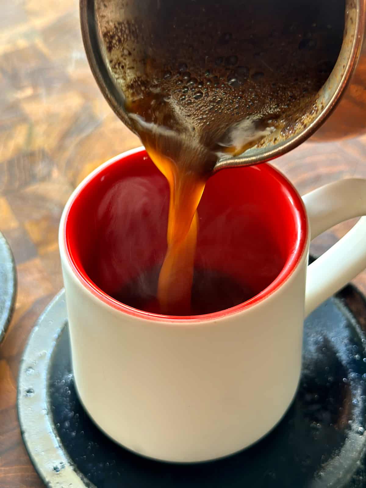 Coffee is poured in a white cup with red walls.