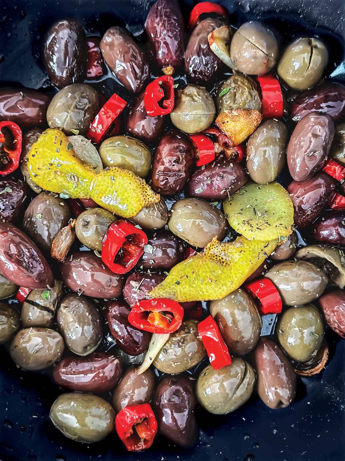 Olives, sliced garlic, chili pepper and lemon peel in a skillet with olive oil.