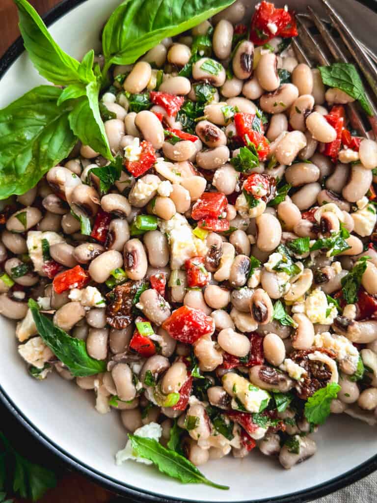 A black eyed pea salad and fresh basil in a plate.