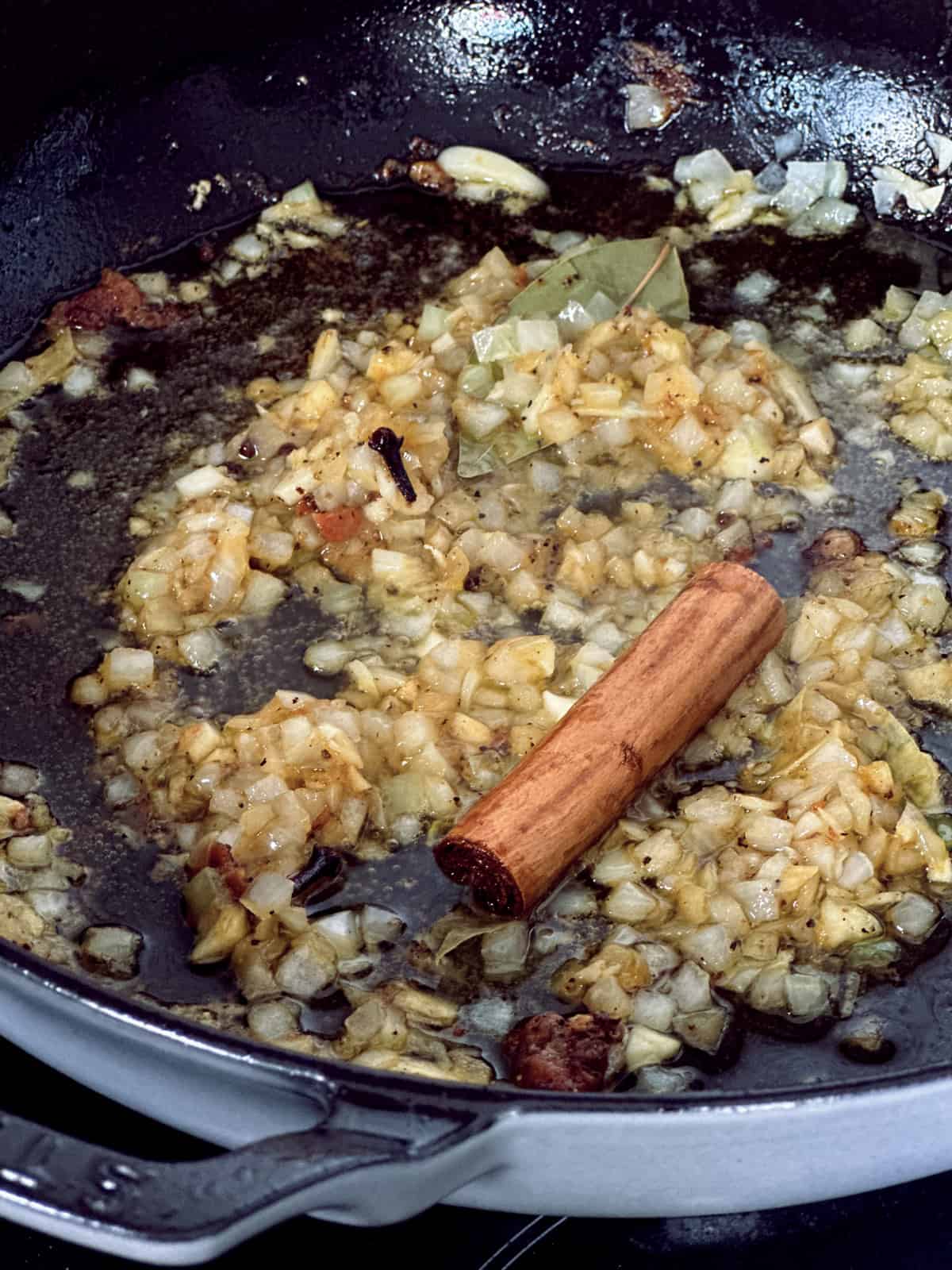 Diced o ions and garlic and a cinnamon stick in a skillet with olive oil.